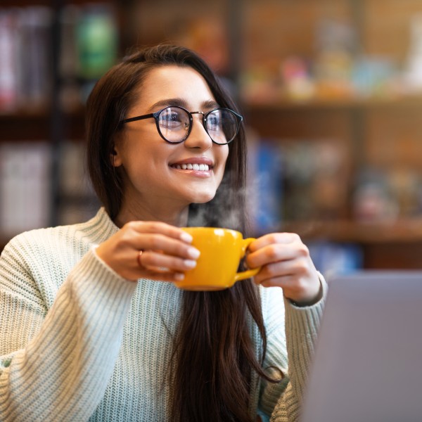 Frau mit Tasse sitzt vor Laptop