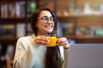 Frau mit Tasse sitzt vor Laptop