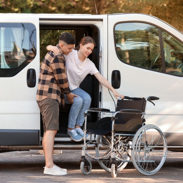 frau wird aus dem fahrzeug in den rollstuhl gehieft