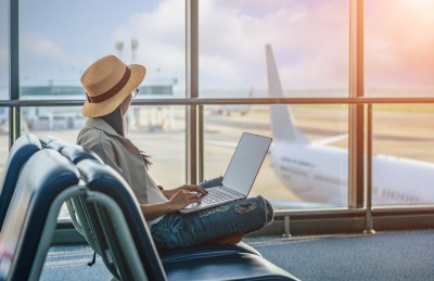 frau sitzt am flughafen mit laptop auf dem schoss