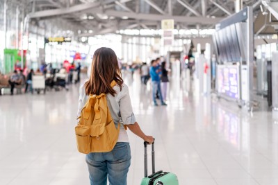 frau läuft am flughafen mit ihrem koffer