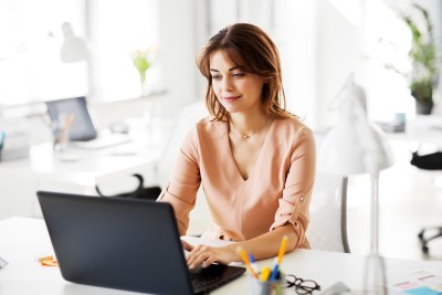 frau sitzt am schreibtisch vor dem laptop