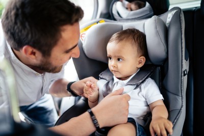 kind wird vom vater im kindersitz angeschnallt