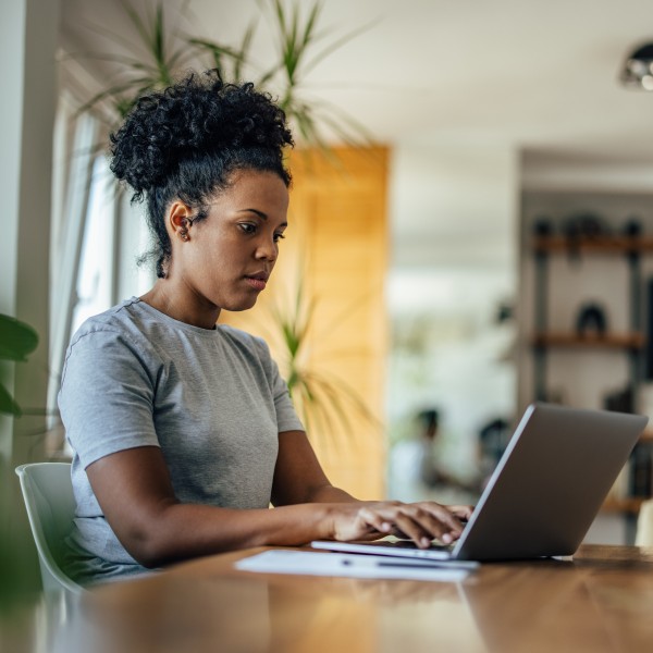 frau sitzt am schreibtisch und recherchiert am laptop
