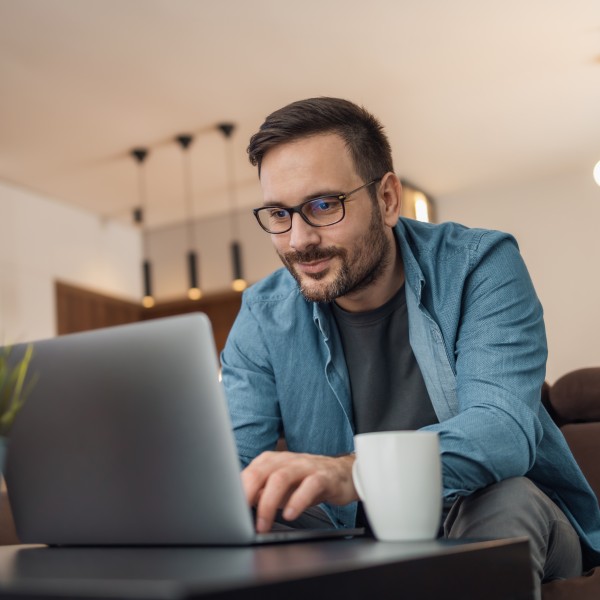 mann sitzt auf der couch vor dem laptop