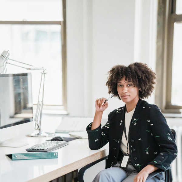 frau sitzt am schreibtisch uns schaut in die kamera