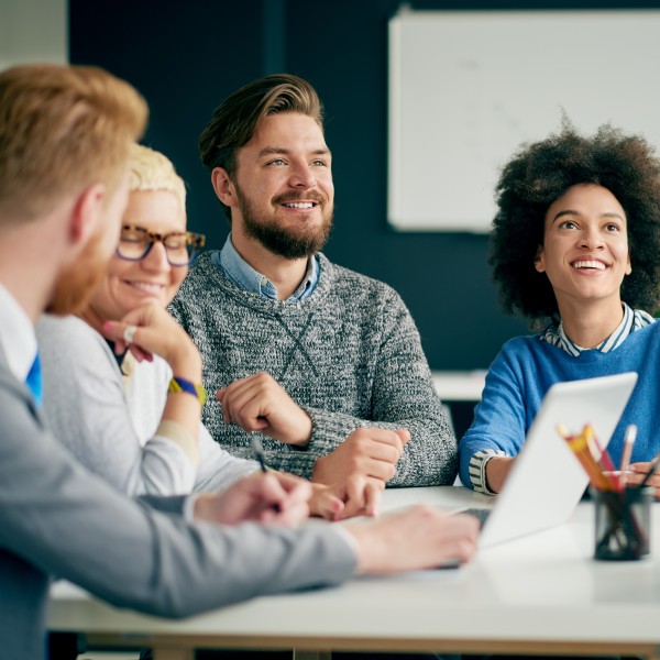 mitarbeiter sitzen an einem tisch und schauen zu einer stehenden person