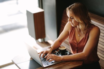 frau sitzt am laptop mit tanktop