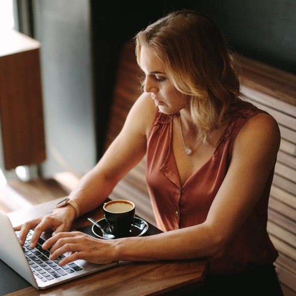 frau sitzt am laptop mit tanktop