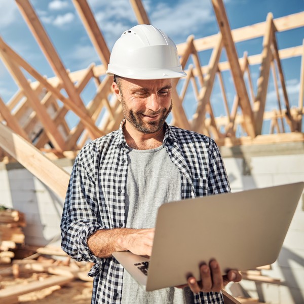 mann hält einen laptop in den händen auf der baustelle