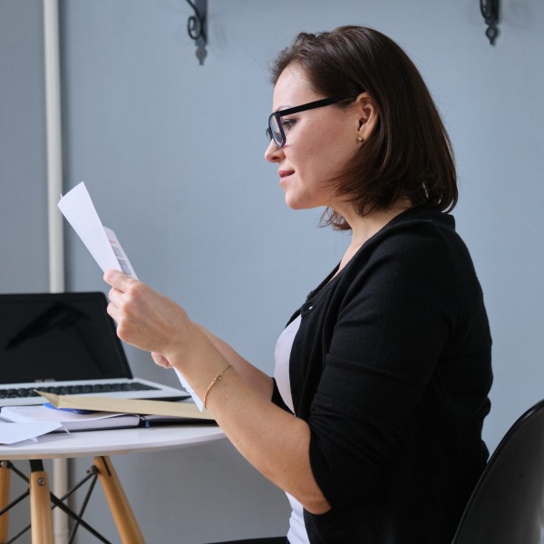 frau sitzt am schreibtisch und liest sich unterlagen durch