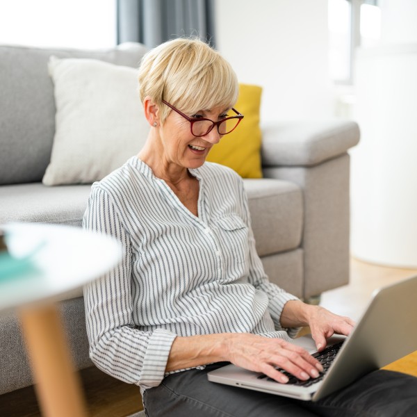 frau sitzt auf dem boden mit laptop auf dem schoss und recherchiert