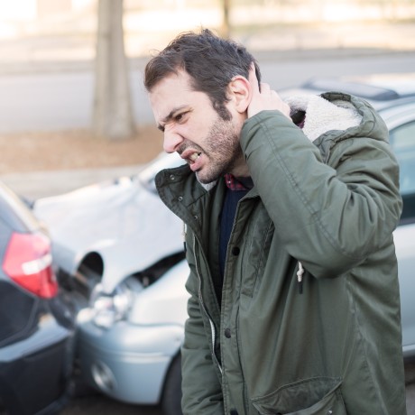 mann greift sich an den nacken nach einem autounfall