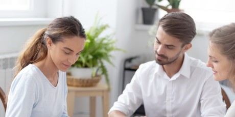 drei menschen sitzen am tisch und schliessen einen vertrag ab