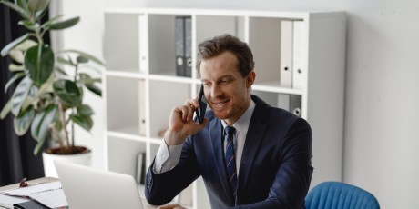 anwalt sitzt am schreibtisch mit smartphone am ohr