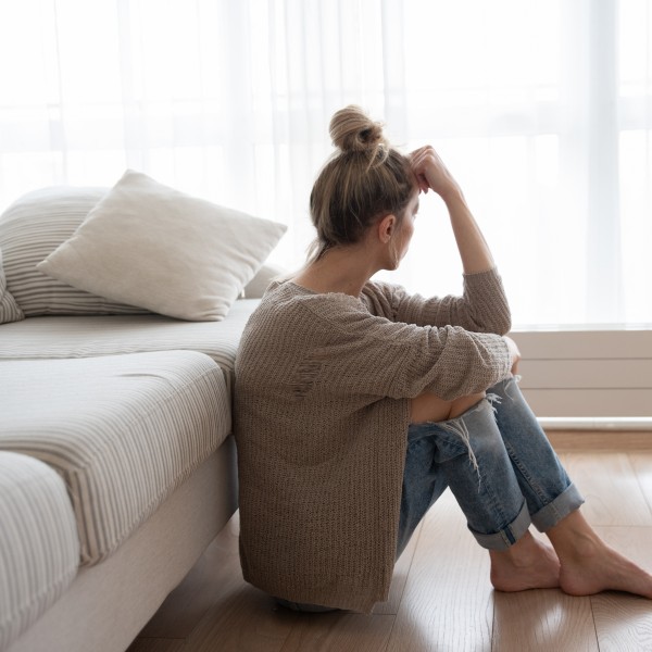 Frau sitzt vor Sofa auf dem Boden