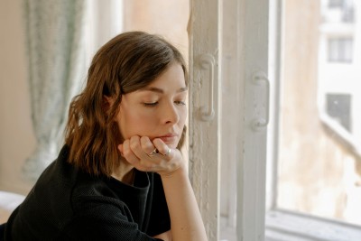 frau sitzt am fenster und denkt nach