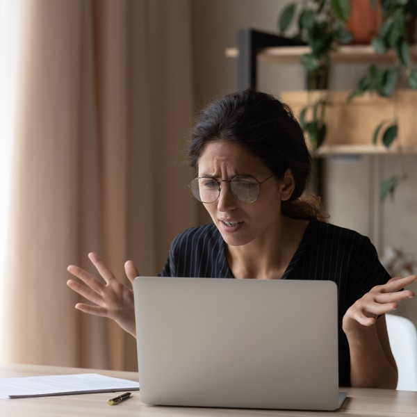 Frau sitzt vor Rechner und bemerkt Anlagebetrug