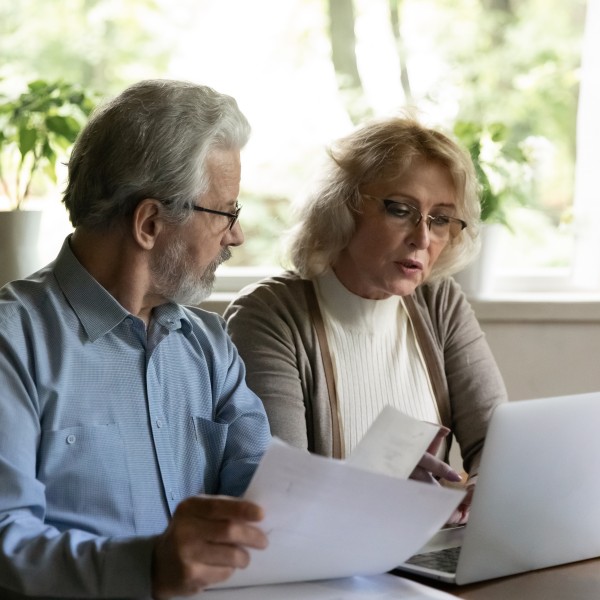 Paar schaut gemeinsam auf Riester-Vertrag und Notebook