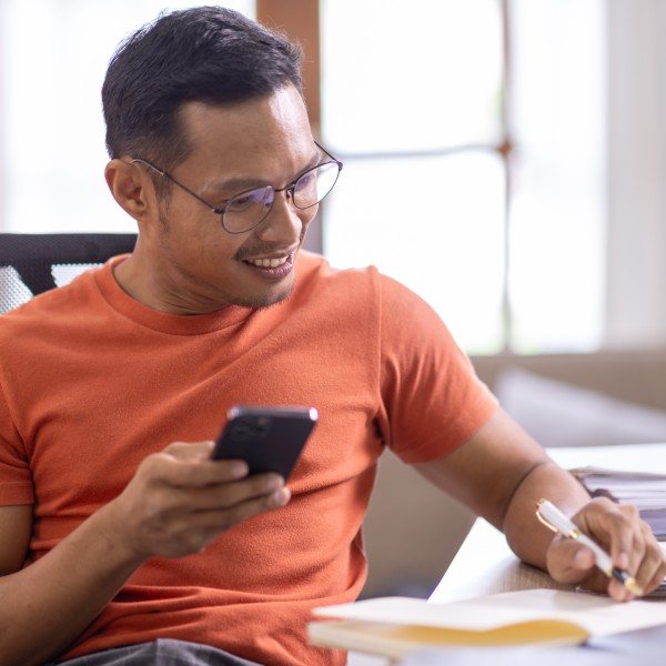 Mann mit Handy in der Hand macht sich Notizen