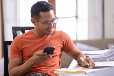 Mann mit Handy in der Hand macht sich Notizen