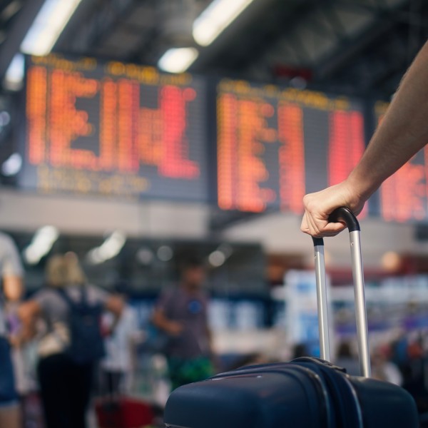 Mann mit Koffer in der Hand vor gestrichenen Flügen