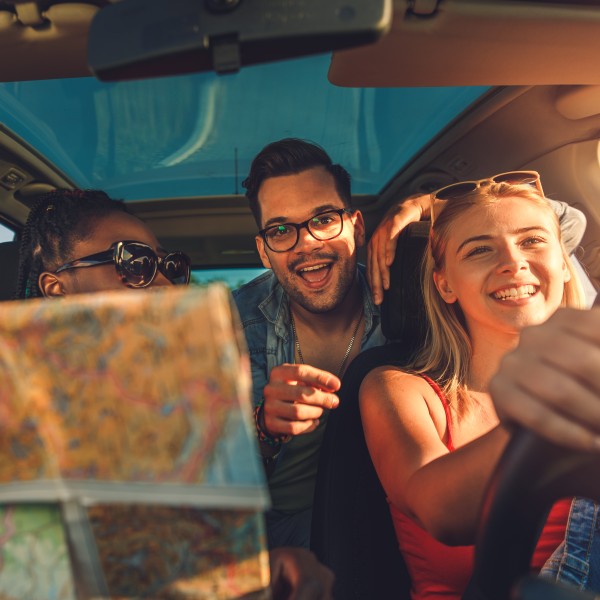 Drei Personen auf dem Weg mit dem Auto in den Urlaub