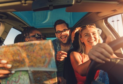 Drei Personen auf dem Weg mit dem Auto in den Urlaub