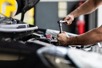 Person schraubt am Auto herum