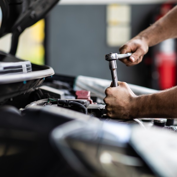 Person schraubt am Auto herum