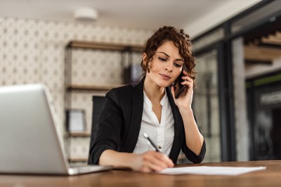 Frau telefoniert und macht sich Notizen