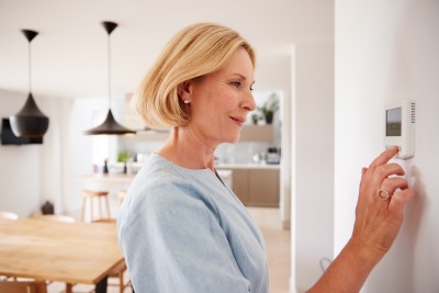 Frau am Thermostat in der Wohnung
