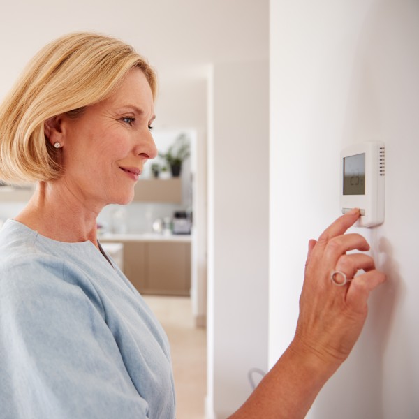 Frau am Thermostat in der Wohnung