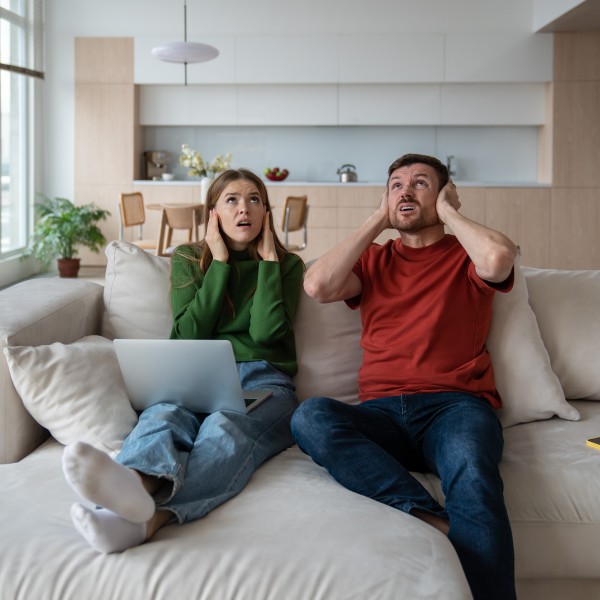 Paar sitzt auf dem Sofa und hält sich die Ohren zu