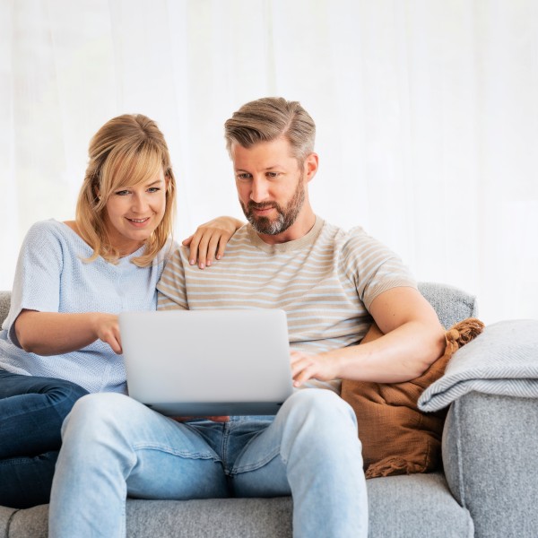 Paar sitzt auf dem Sofa mit Laptop