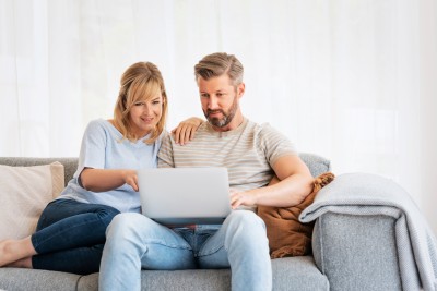 Paar sitzt auf dem Sofa mit Laptop