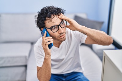 Mann schaut nachdenklich am Telefon